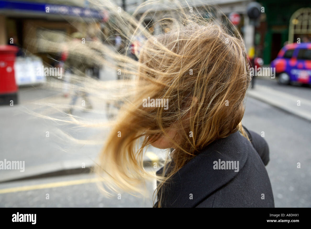 A gust of wind blows a woman's hair sideways outside Liverpool Street Station London Stock Photo