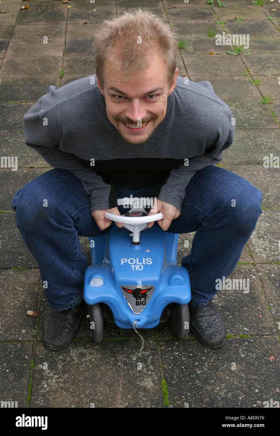 Man on toy car Stock Photo