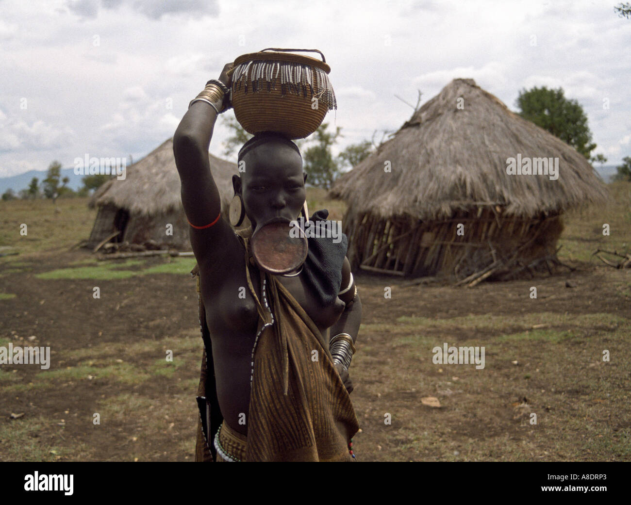 Mursi tribe woman with lip plate and basket on her head Ethiopia Stock Photo