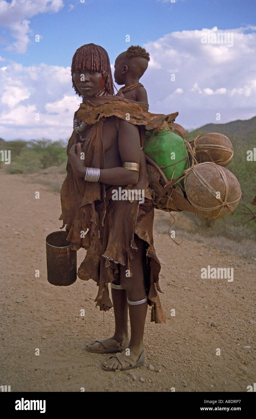 Turmi Hamar tribe woman with baby and water container strapped on her back Omo river region Ethiopia Stock Photo