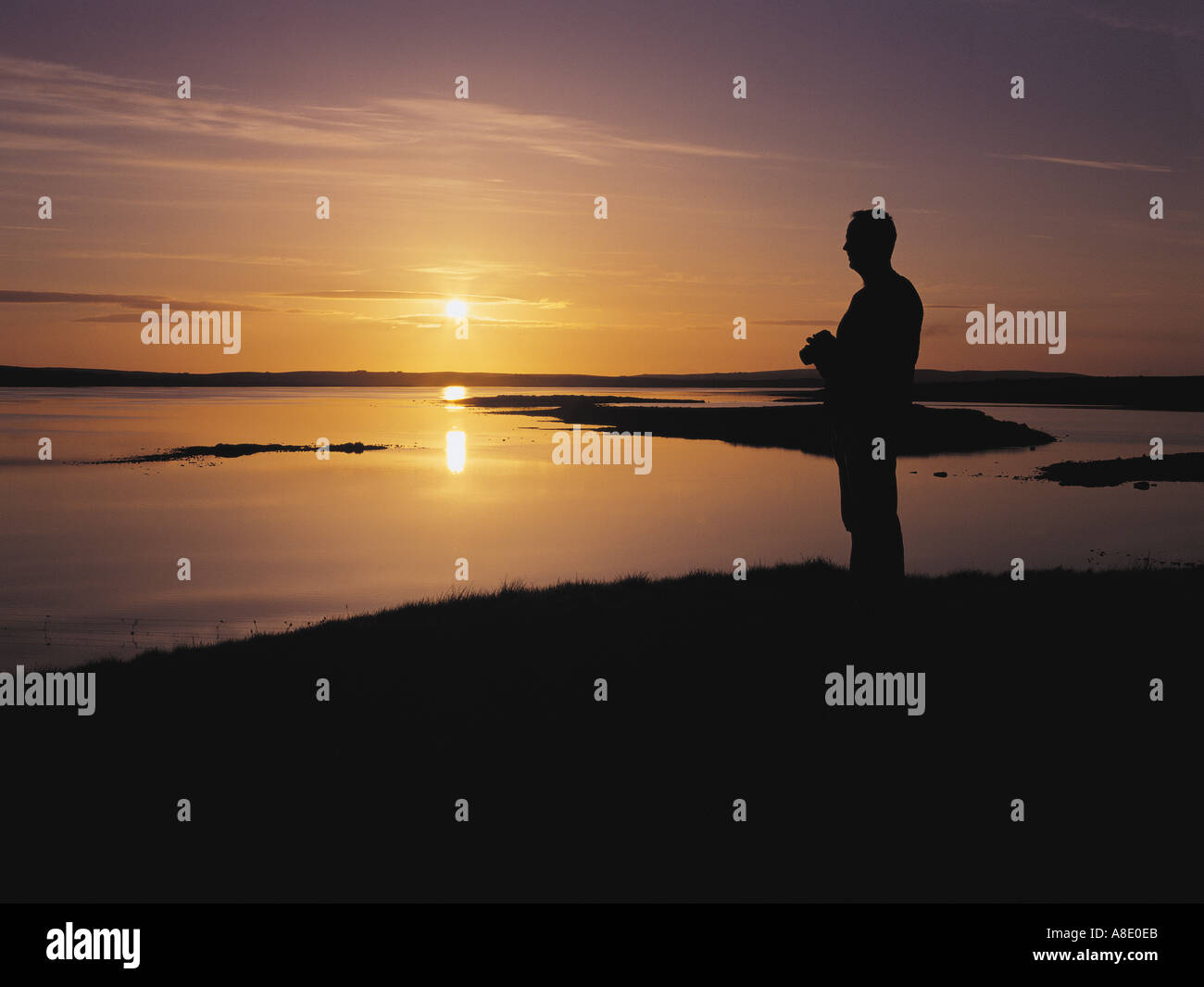 dh Loch of Harray STENNESS ORKNEY Scotland Tourist with camera watching sunset at Lochside nature reserve uk photographing bird birdwatching Stock Photo