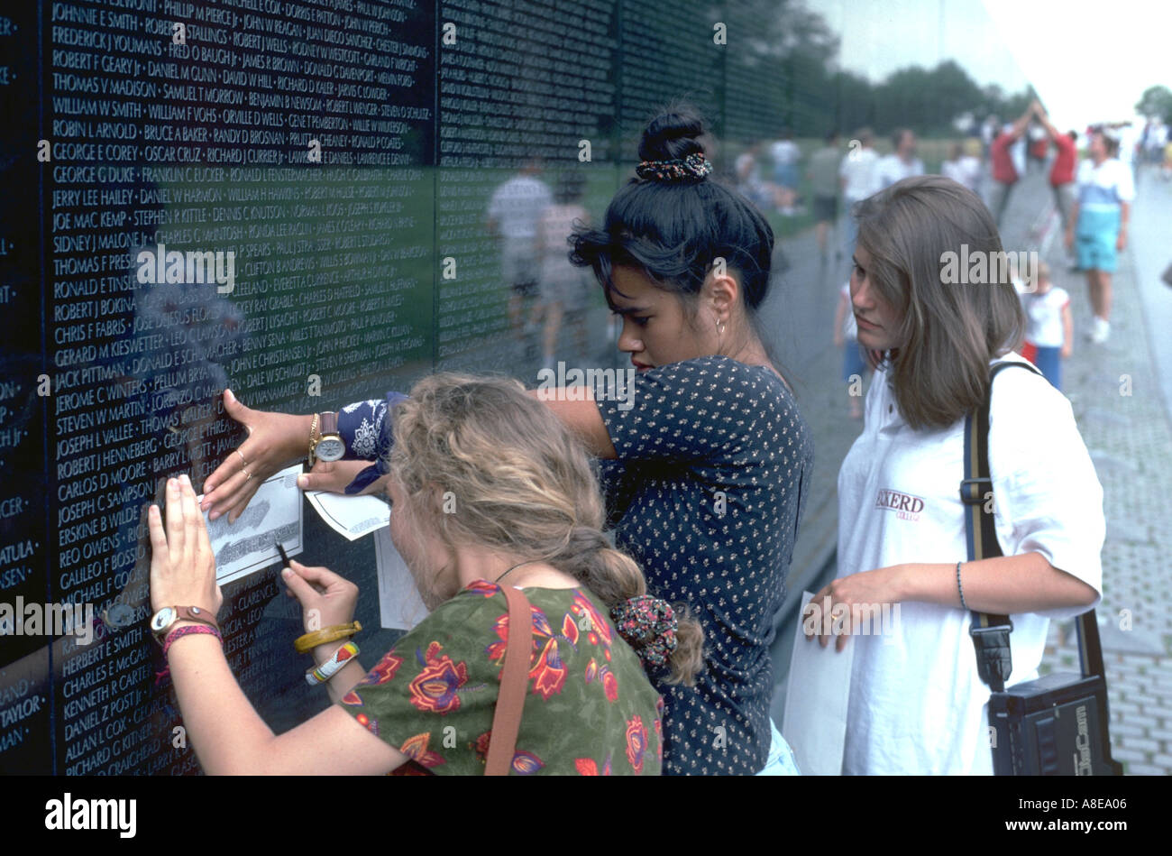Visitors age 20 making rubbing at national Vietnam war memorial. Washington DC USA Stock Photo