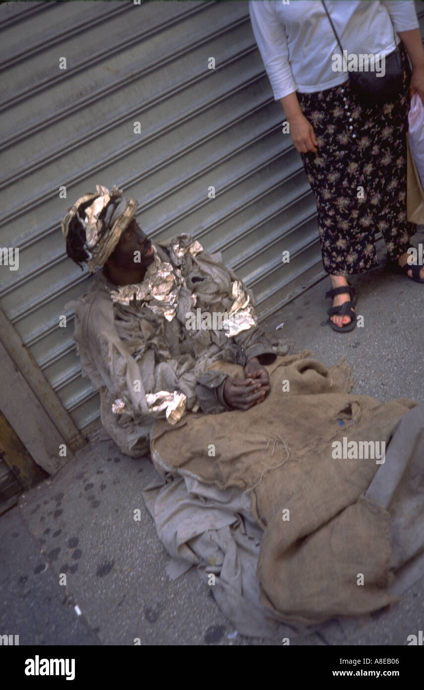 Homeless beggar age 38 in rags sitting on sidewalk. New York New York USA Stock Photo