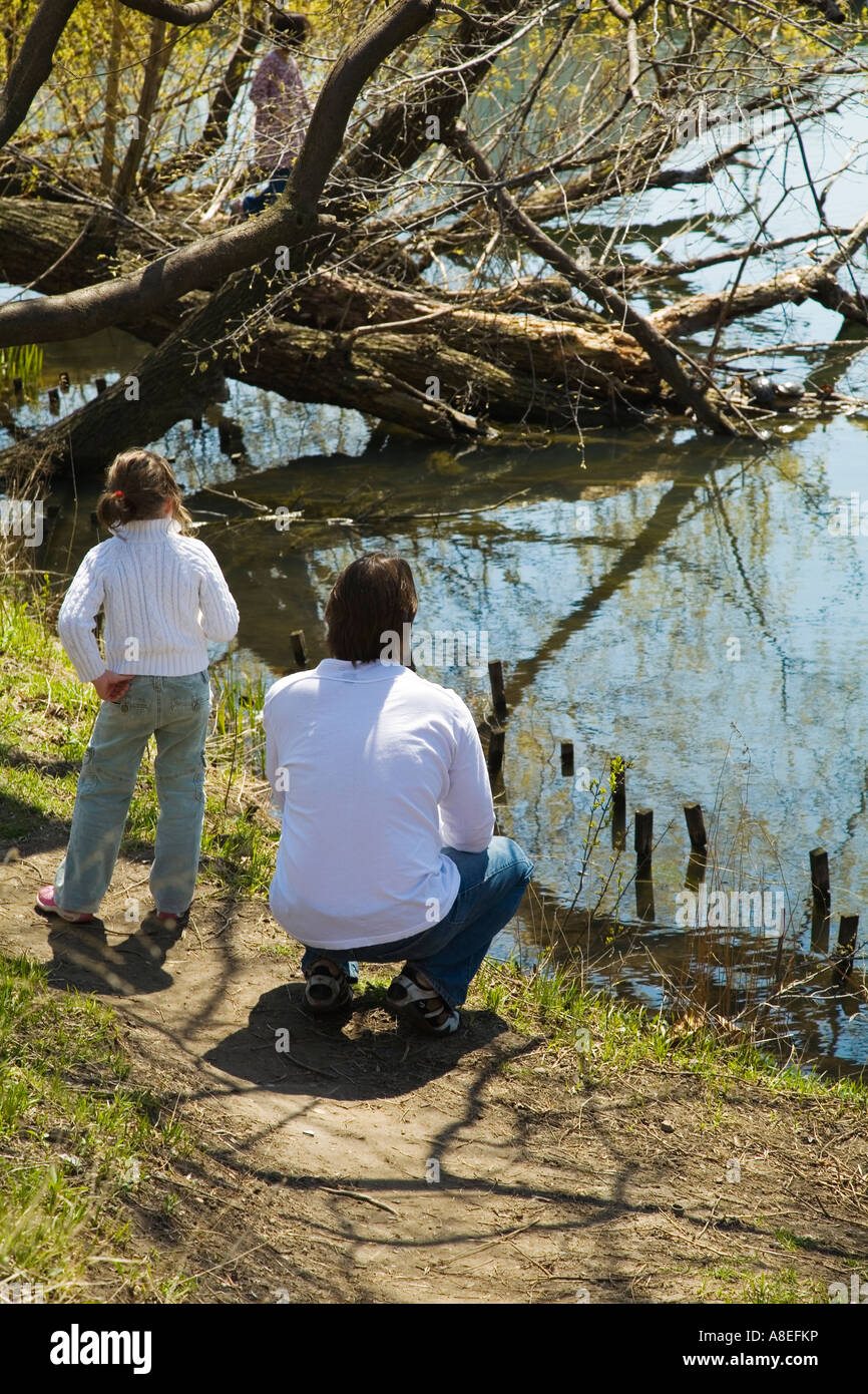 CHICAGO Illinois Young girl and father look at turtles on log in water lagoon in Lincoln Park Stock Photo