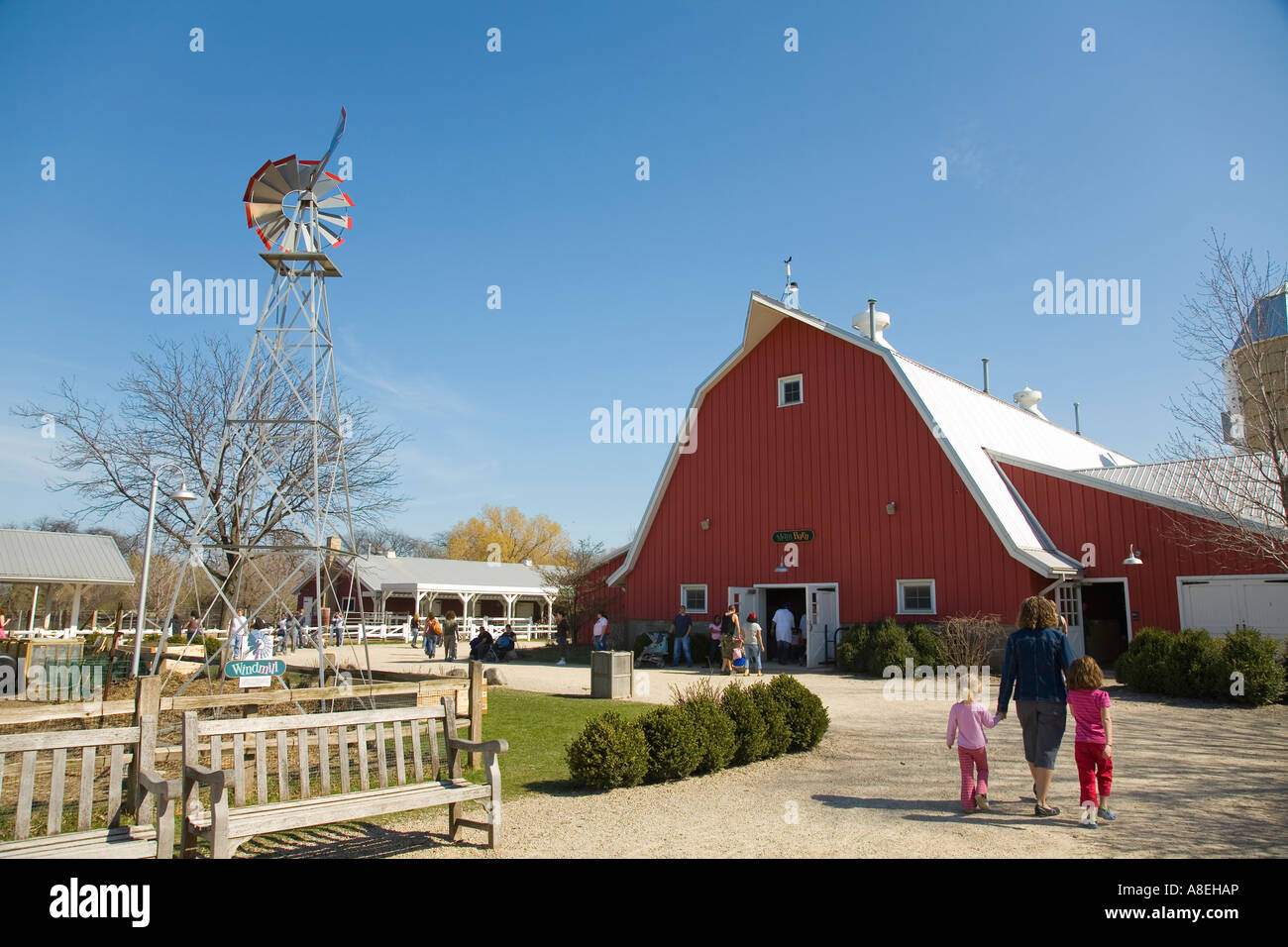 CHICAGO Illinois Red barn at Farm in the Zoo section of Lincoln Park Zoo adult woman hold hands of two girls wind mill Stock Photo
