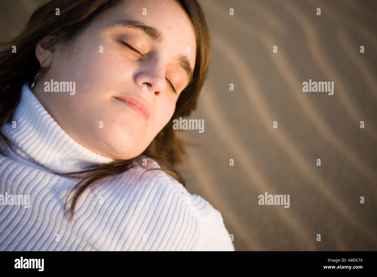 Young woman laid on the sand enjoying the sun on her face Stock Photo ...