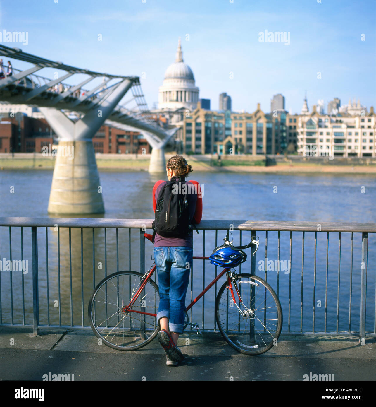 A cyclist watching the Thames River by the Millennium Bridge in London England UK  KATHY DEWITT Stock Photo