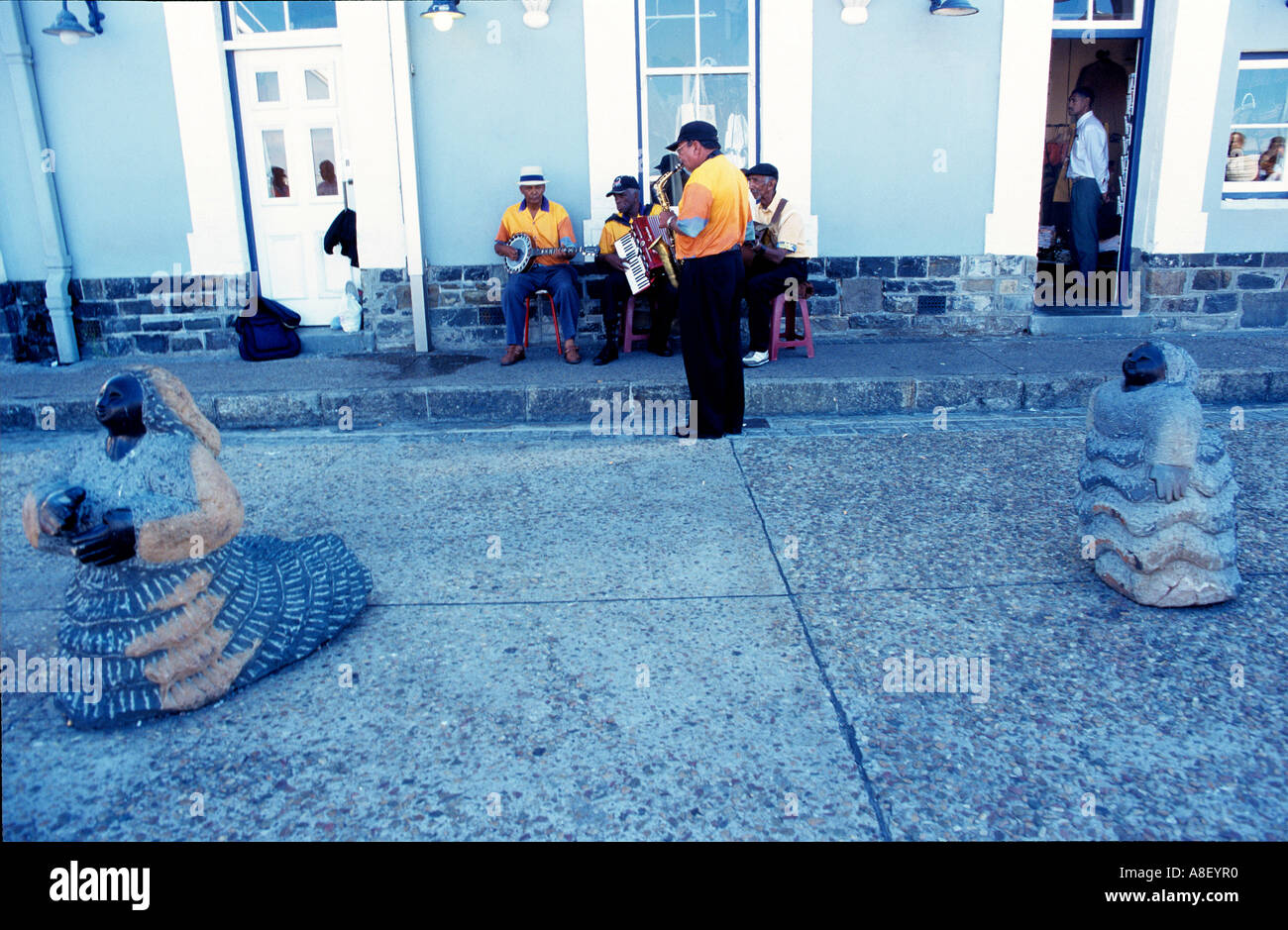 A small Jazz band perform for tourists behind a stone sculpture on the V&A Waterfront, Cape Town, South Africa. Stock Photo