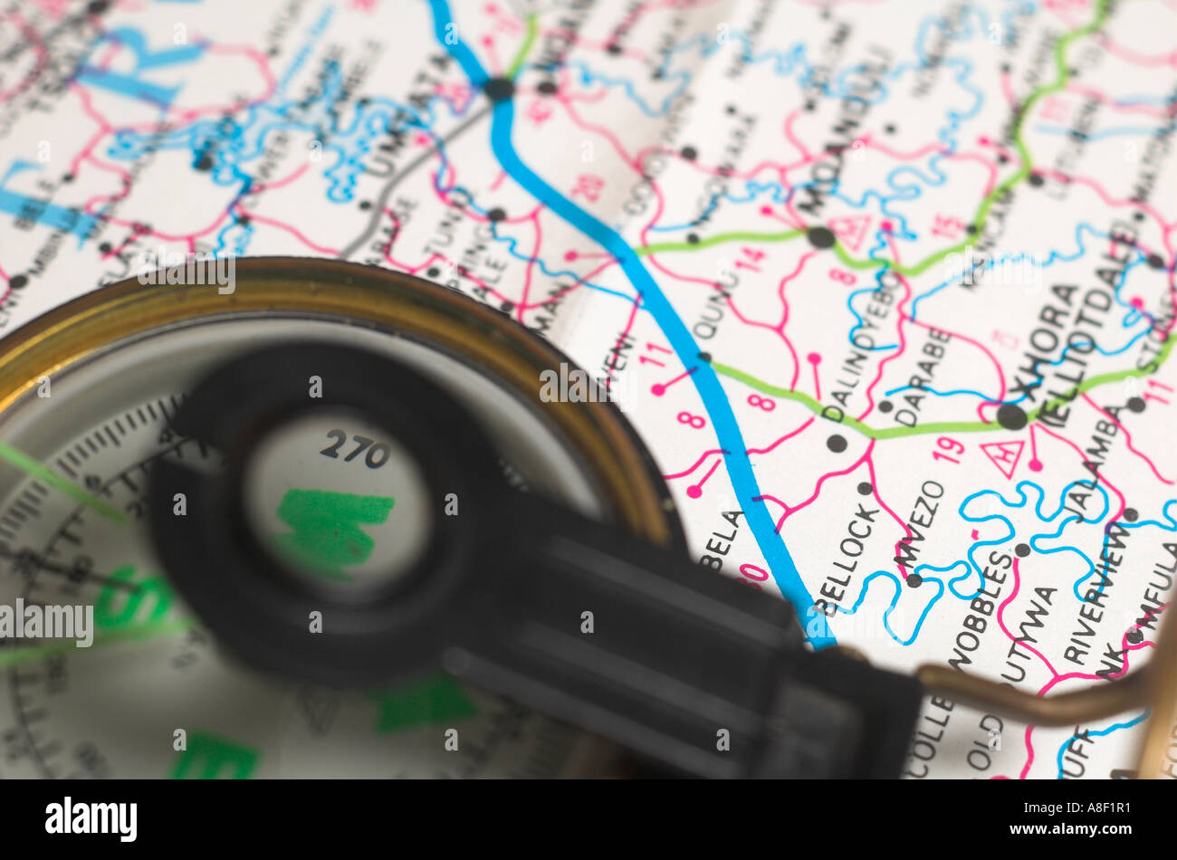 A needle compas lies on top of a colourful map Stock Photo - Alamy