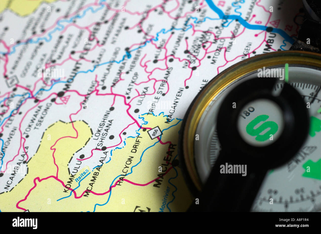 A needle compas lies on top of a colourful map Stock Photo - Alamy