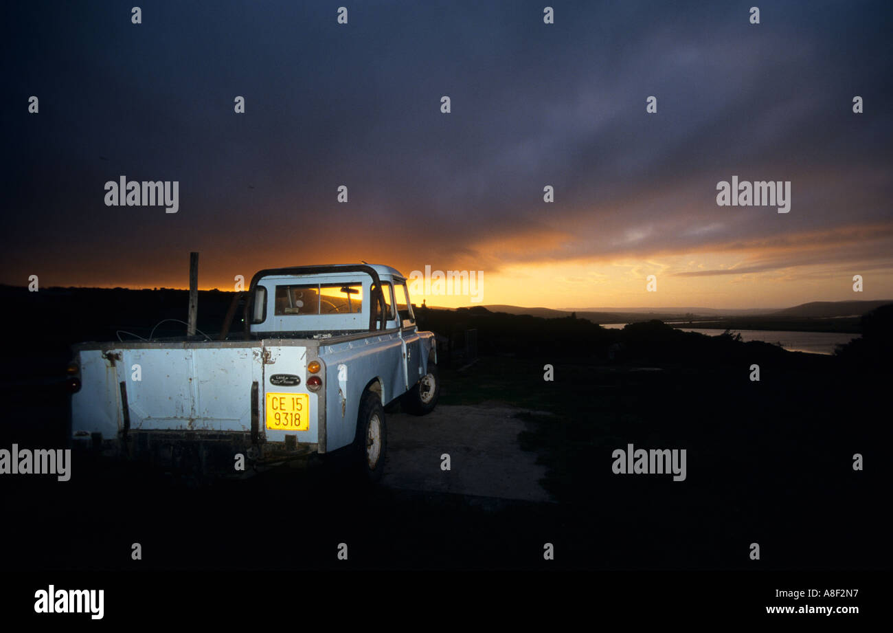 An original Land Drover defender stands in front of a stunning sunset. Stock Photo