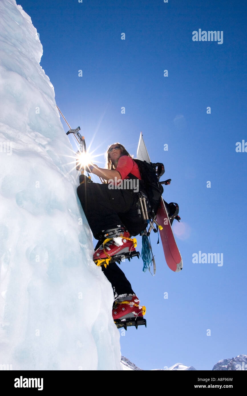 Female Mountaineer ascending Ice Climb with Snowboard on Backpack Stock