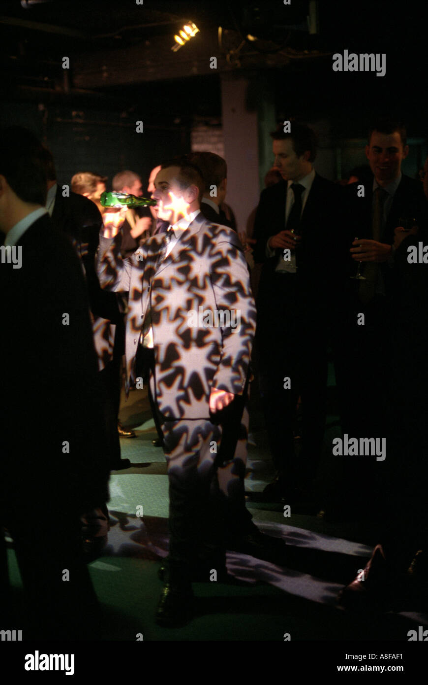 A businessman drinking from a bottle of beer at a business reception held at the London Aquarium, London, UK. Stock Photo