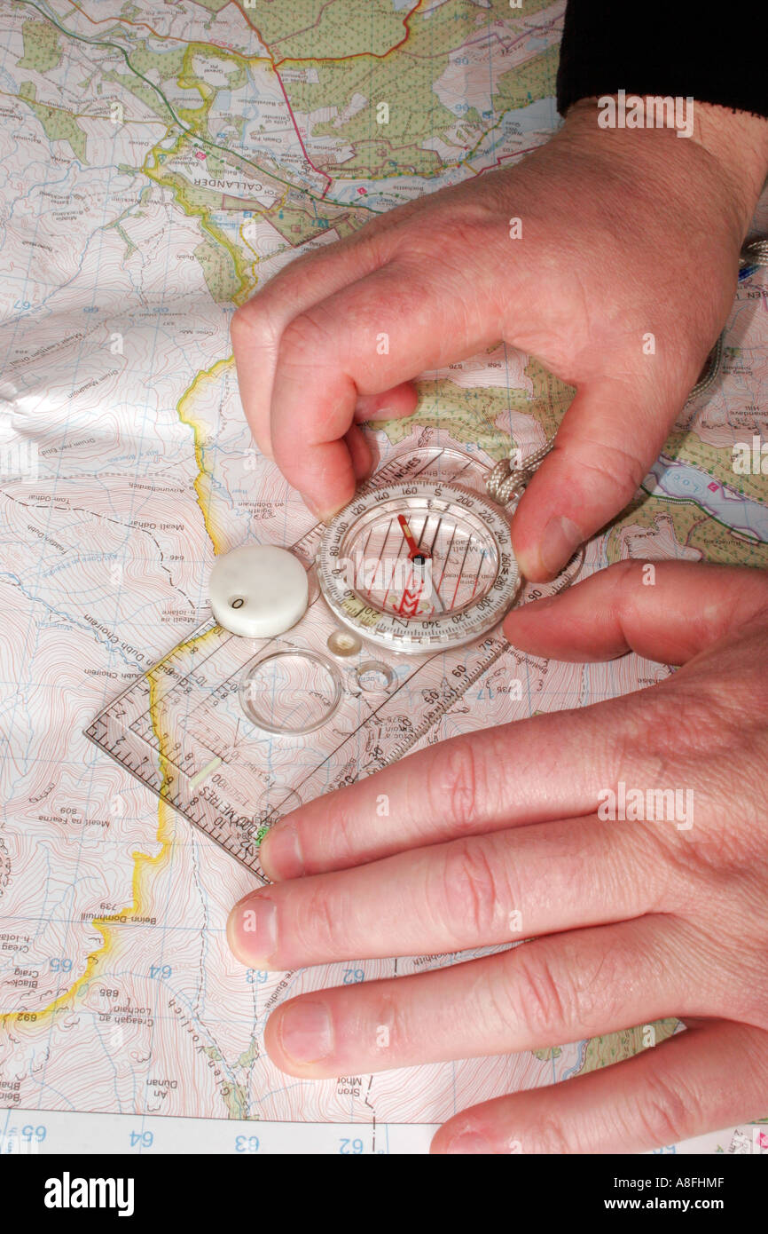 Close Up of Persons Hands Measuring a Bearing from a Map using a Compass Stock Photo