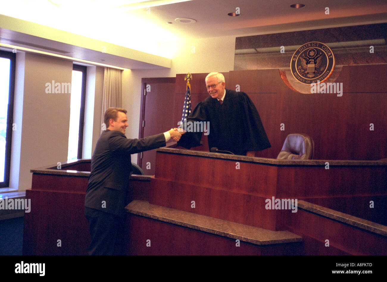 Judge in courtroom shaking hands with newly sworn in young lawyer age 63 and 32. St Paul Minnesota USA Stock Photo