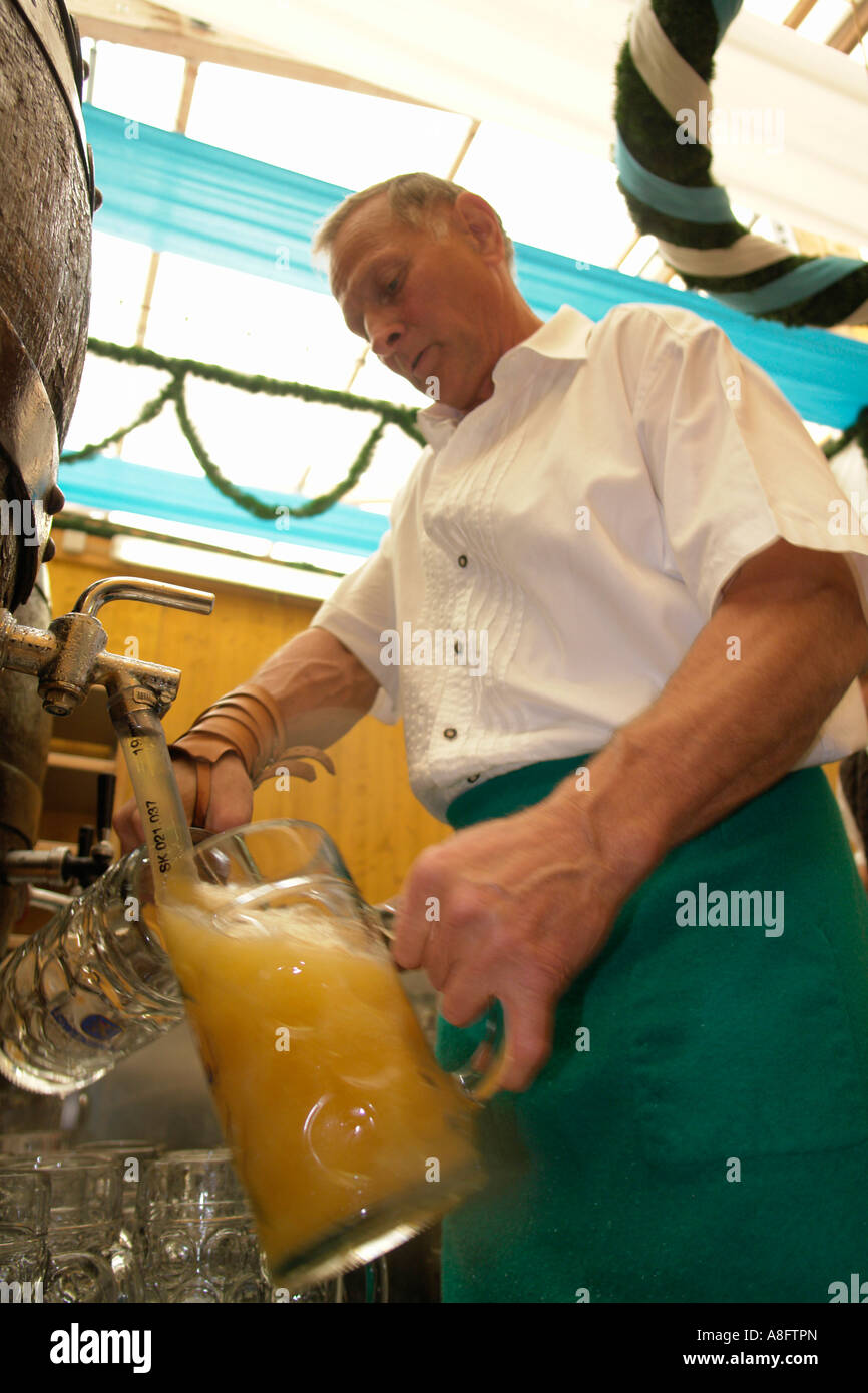 Bar tender at Munich Beer Festival Oktoberfest  busy pouring liter beer from Barrel to glasses. Stock Photo