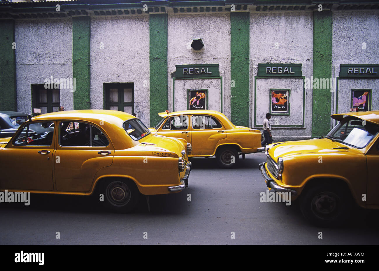Yellow Ambassador Taxis drive along outside the Regal cinema Kolkata Calcutta India Stock Photo