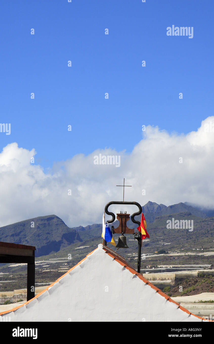 Church bell & flags at Aguadulce Tenerife Canary Islands Spain Los Gigantes cliffs in background Stock Photo