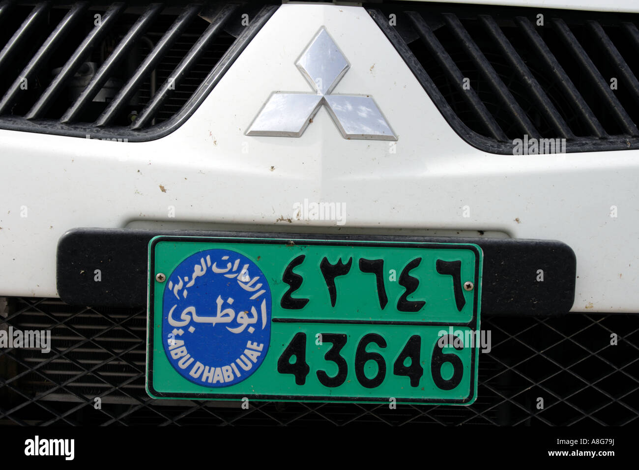 white Mitshubishi car with arabic number license plate of Abu Dhabi