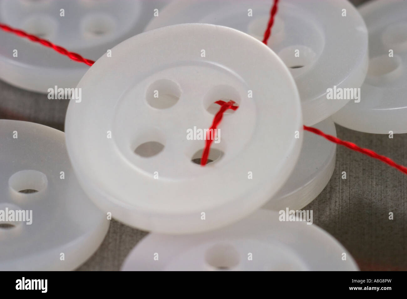 White buttons with a red thread Stock Photo - Alamy