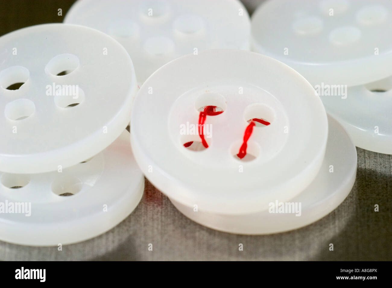 White buttons with red thread Stock Photo - Alamy