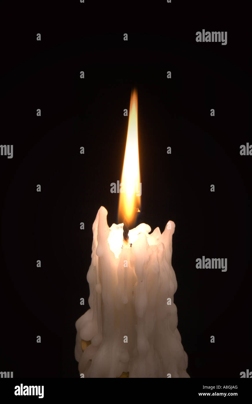 Candle burning against black background. Stock Photo