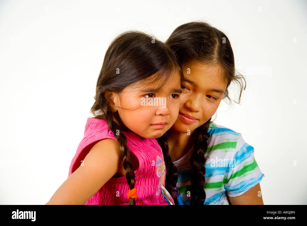 A 13 year old Chinese American California teen comforts her crying 4 year old sister Stock Photo