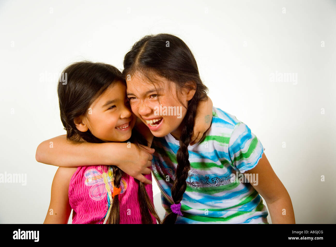 A 13 year old Chinese American California teen hugs her 4 year old sister Stock Photo