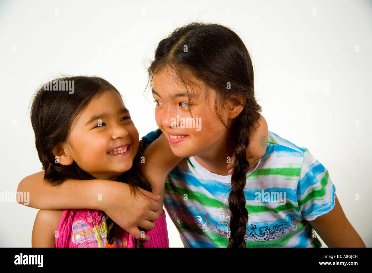 A 13 year old Chinese American California teen hugs her 4 year old sister Stock Photo