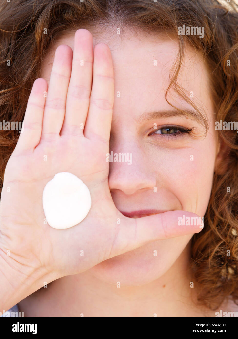 Young woman smiling with blob dab of suncream on her hand Fair skin needs to be protected against uv radiation Stock Photo
