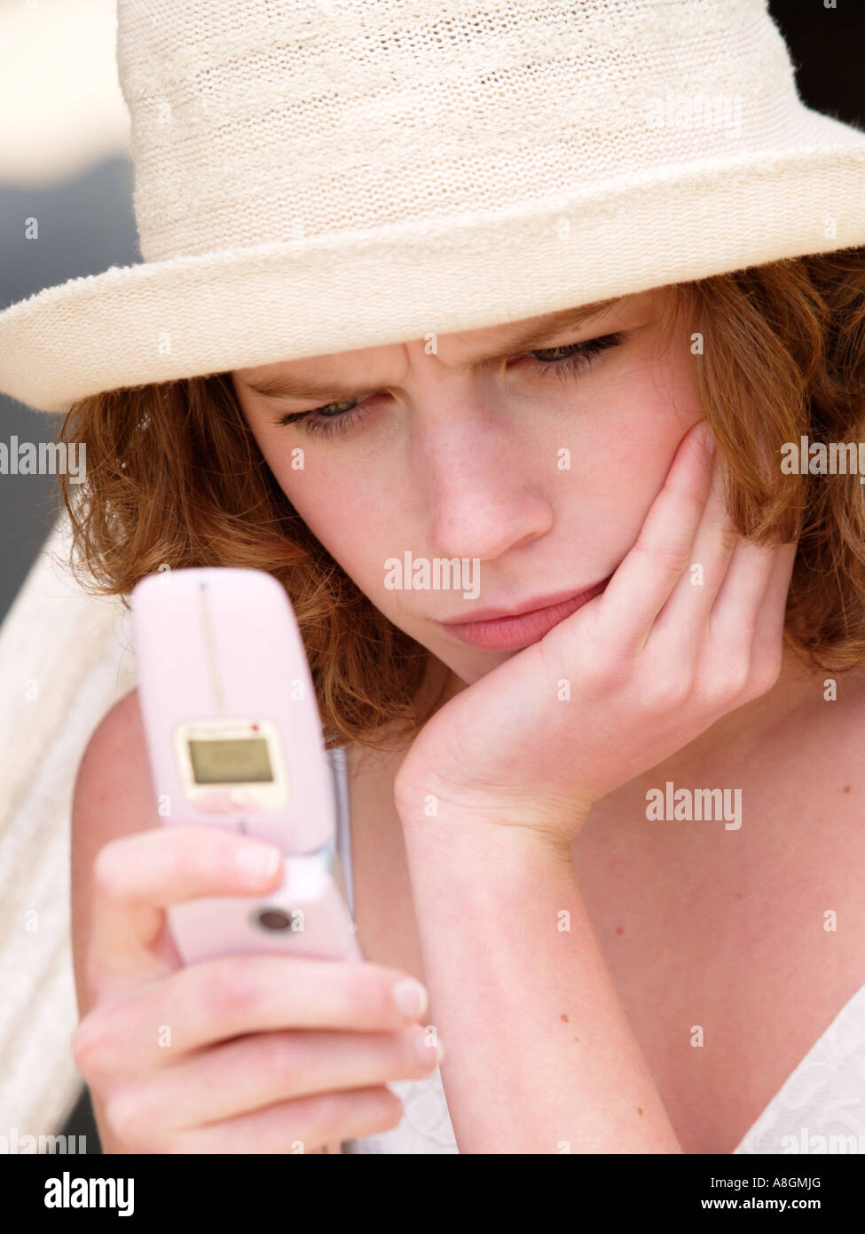 Sad disappointed angry teenage girl young woman reading sms text message on her mobile phone Stock Photo
