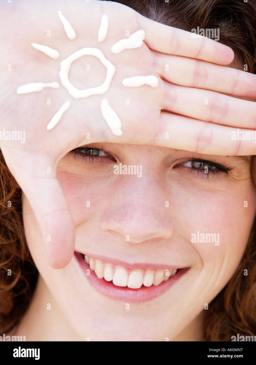 Teenage girl smiling with figure of a sun drawn in suncream on her hand Fair skin needs to be protected against uv radiation Stock Photo