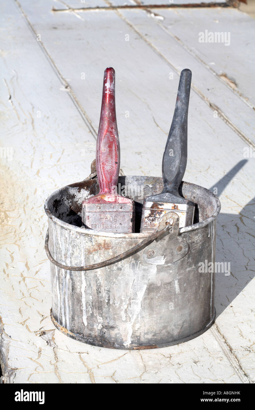 Two paint brushes in paint kettle standing on old wood door Stock Photo