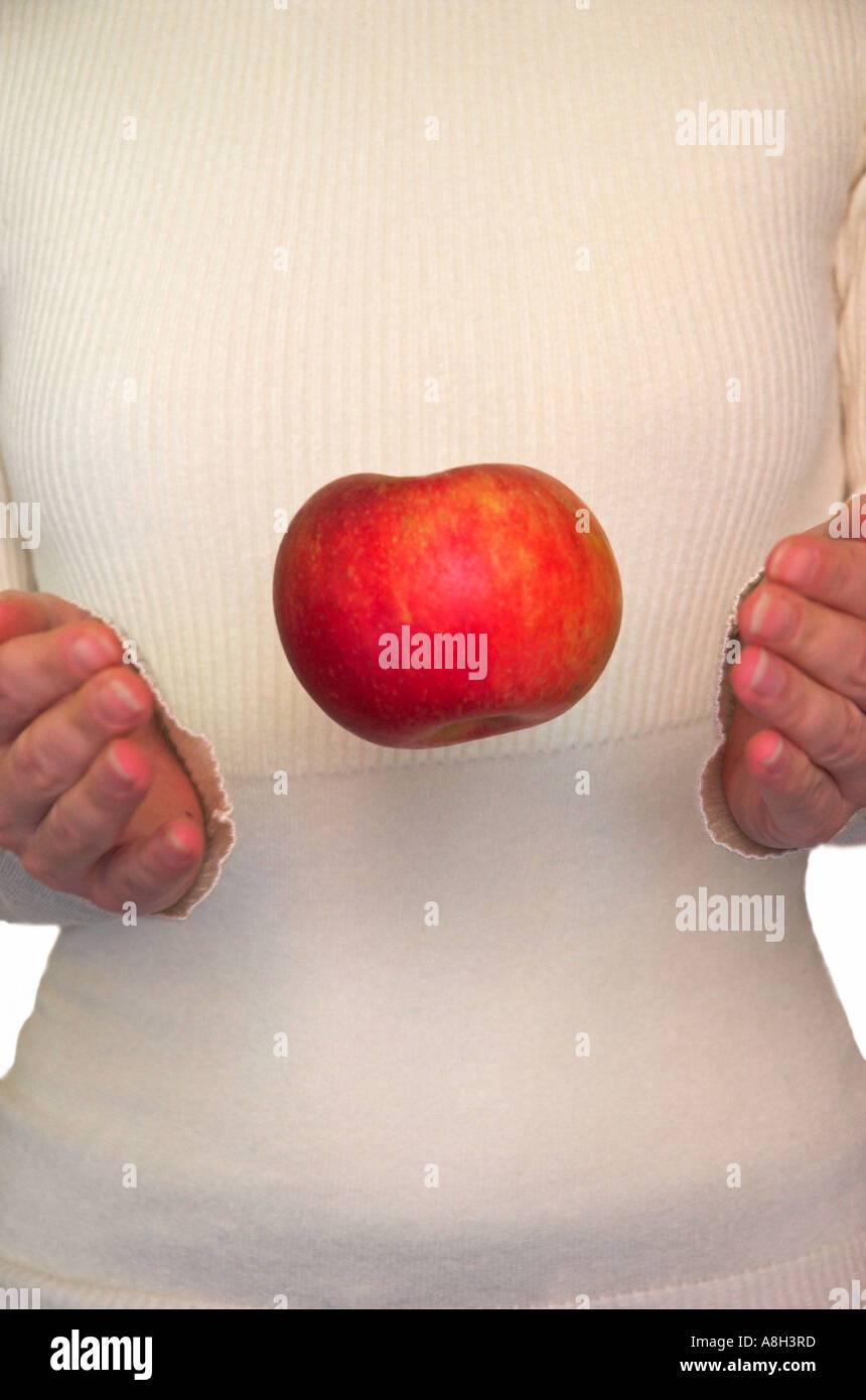 Woman with hands raised around apple suspended in air Stock Photo