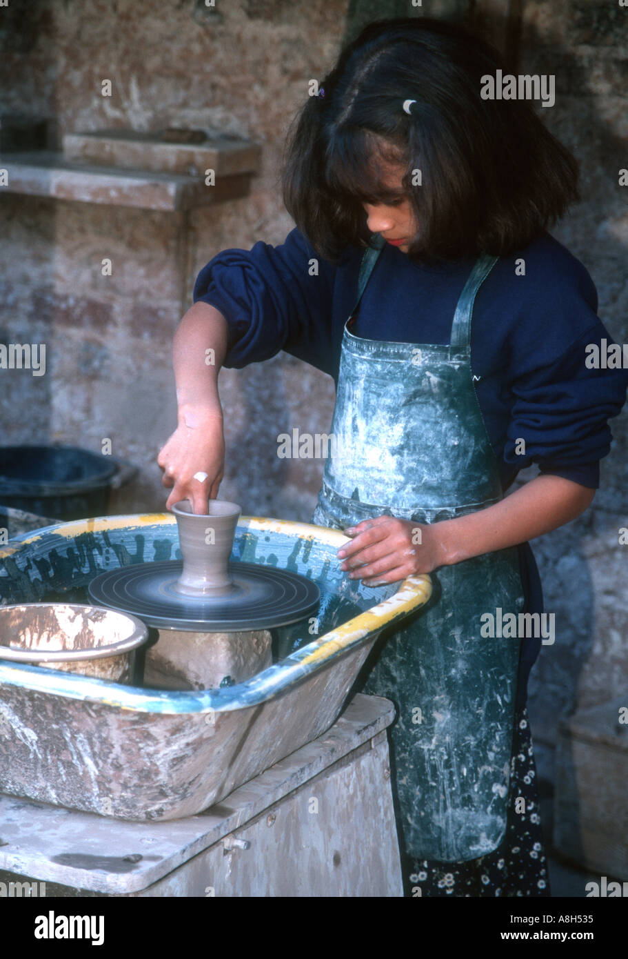 Young girl making vase at spinning pottery wheel Welsh Life Museum