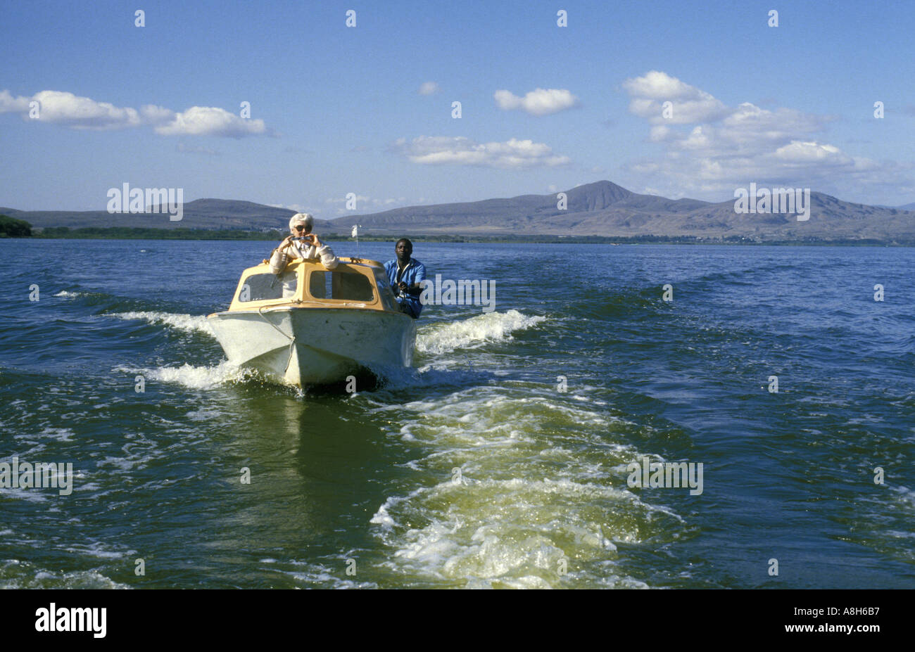 White lady tourist and black African boatman enjoy a motorboat cruise on Lake Naivasha Kenya East Africa Stock Photo