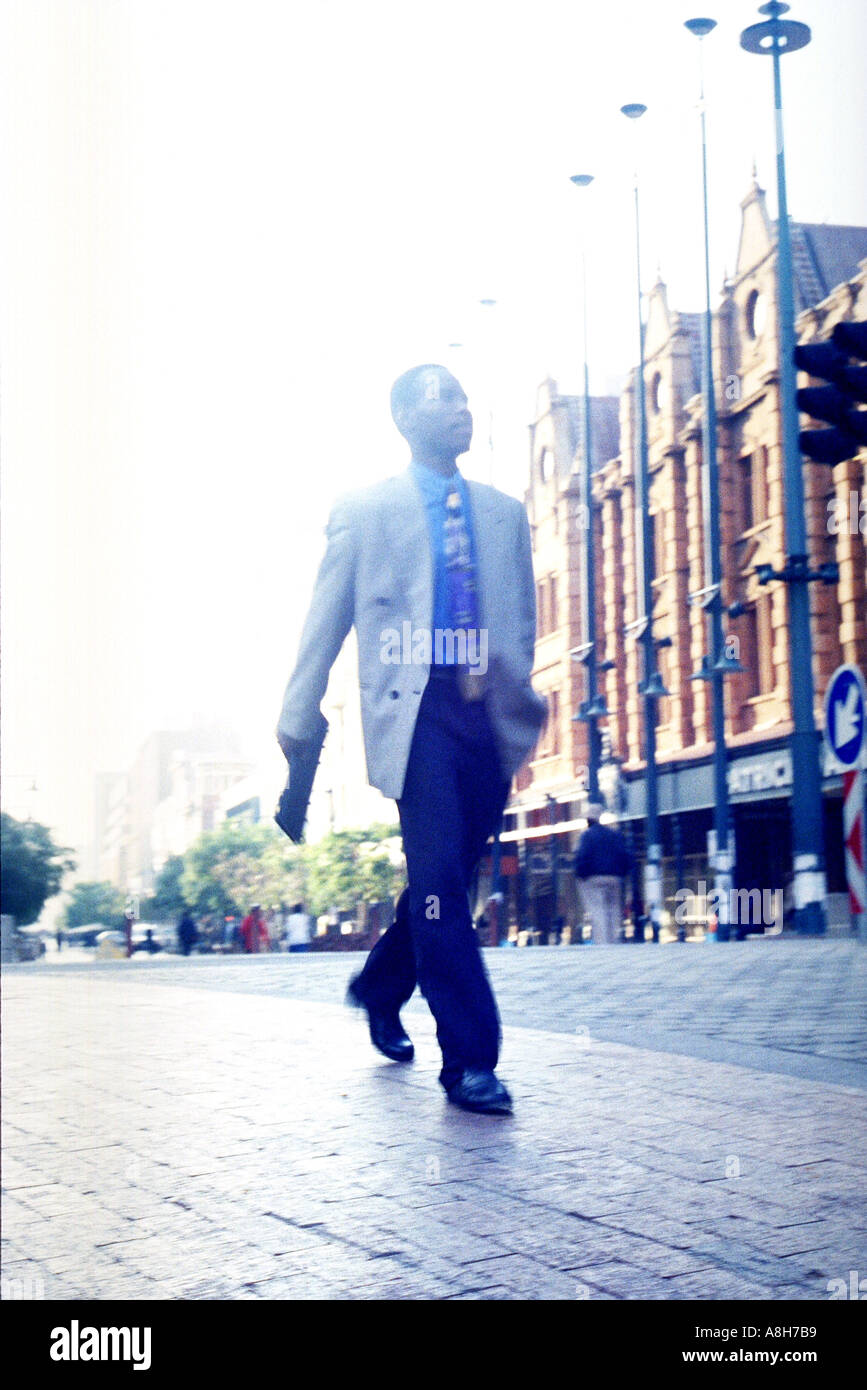 African businessman walking along street pavement Pretoria Gauteng South Africa Africa  Stock Photo