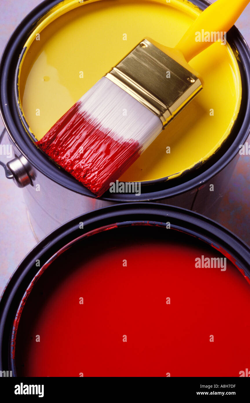 Red paint and yellow paint in cans with paint brush Stock Photo