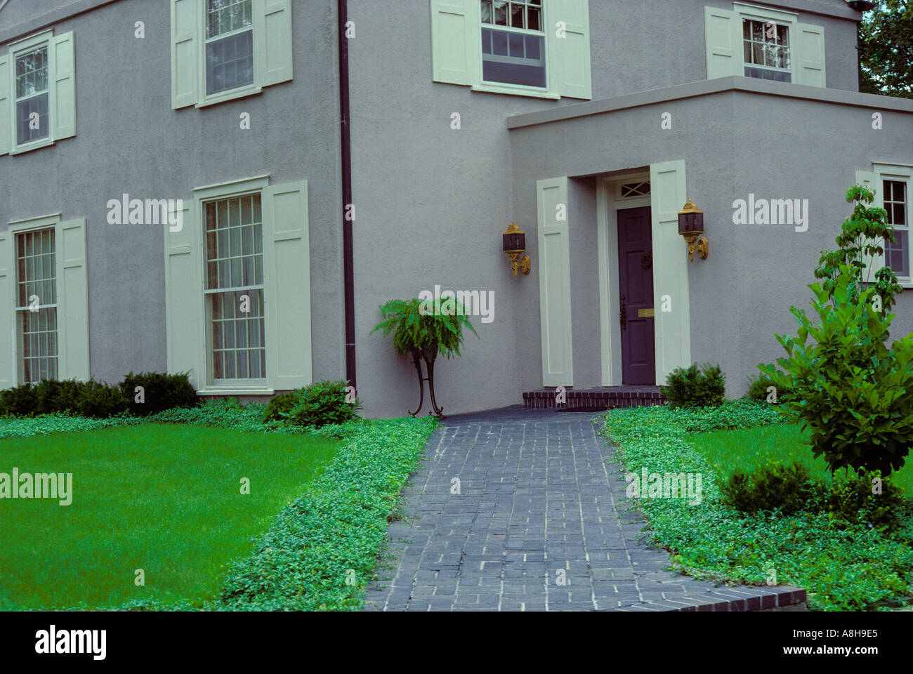 gray painted stucco house with green lawn dark gray brick sidewalk midwest USA Stock Photo