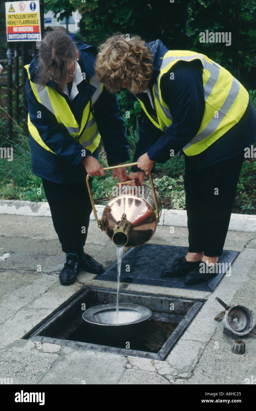 Trading Standards Officers checking fuel at garage England UK Returning petrol to storage tank from copper jugs Stock Photo