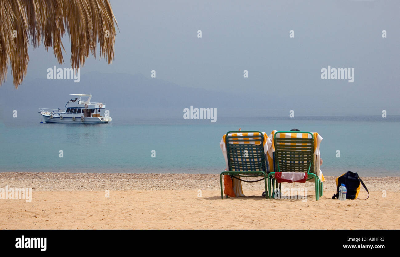 Holidaymakers relaxing on sun loungers on a beach beside the Red Sea at Nuweiba Sinai Egypt Stock Photo
