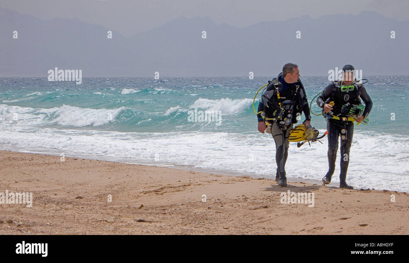 Divers walking along the shoreline on the Red Sea Coast Sinai Egypt Stock Photo