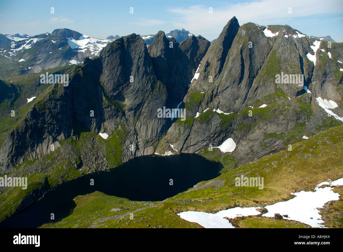 Mountain Munkan with lake and snowfields Moskenesoya Lofoten Norway ...