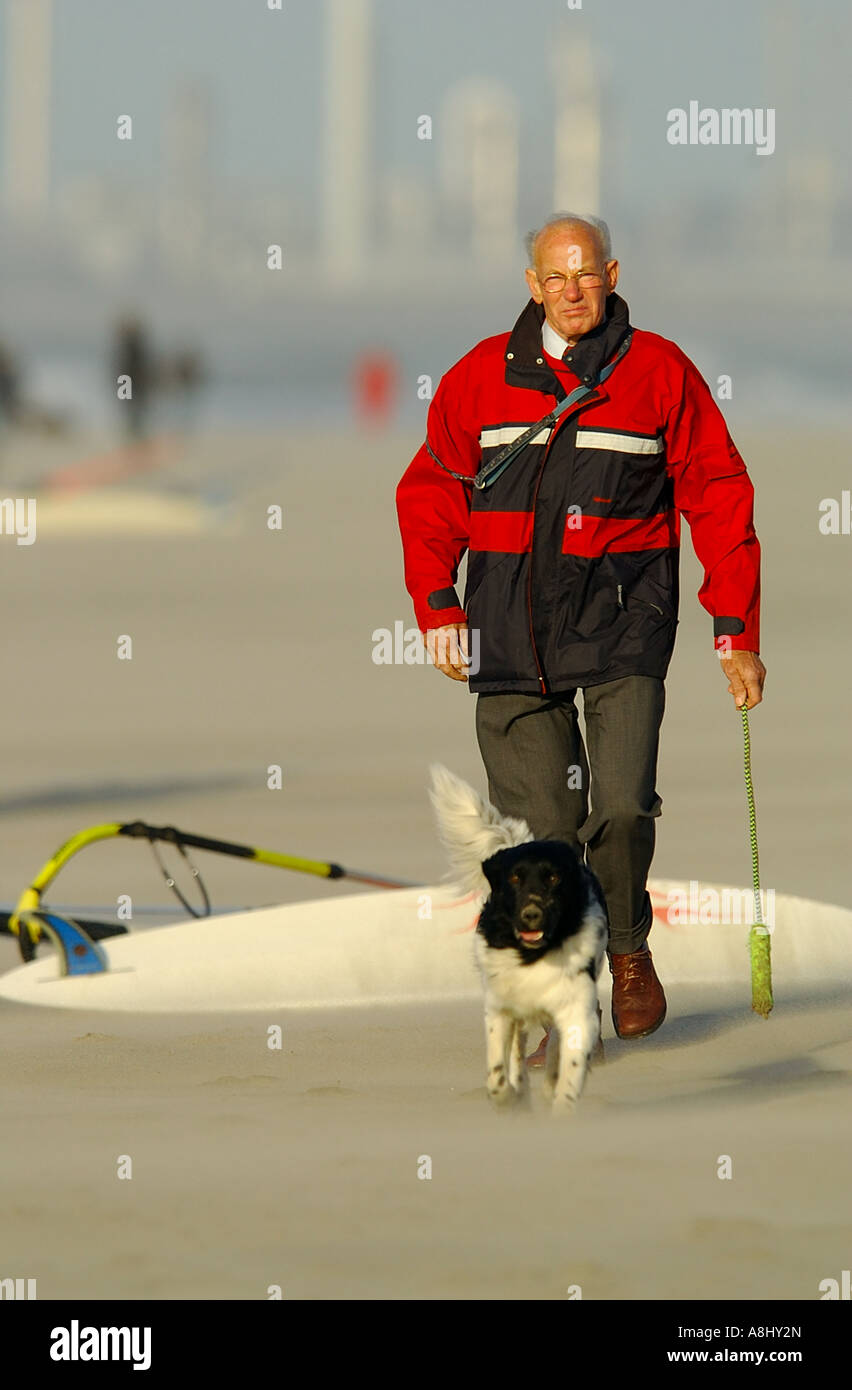 Old people walking on a windy beach old men with red jacket and dog and a  pole in he hand Stock Photo - Alamy