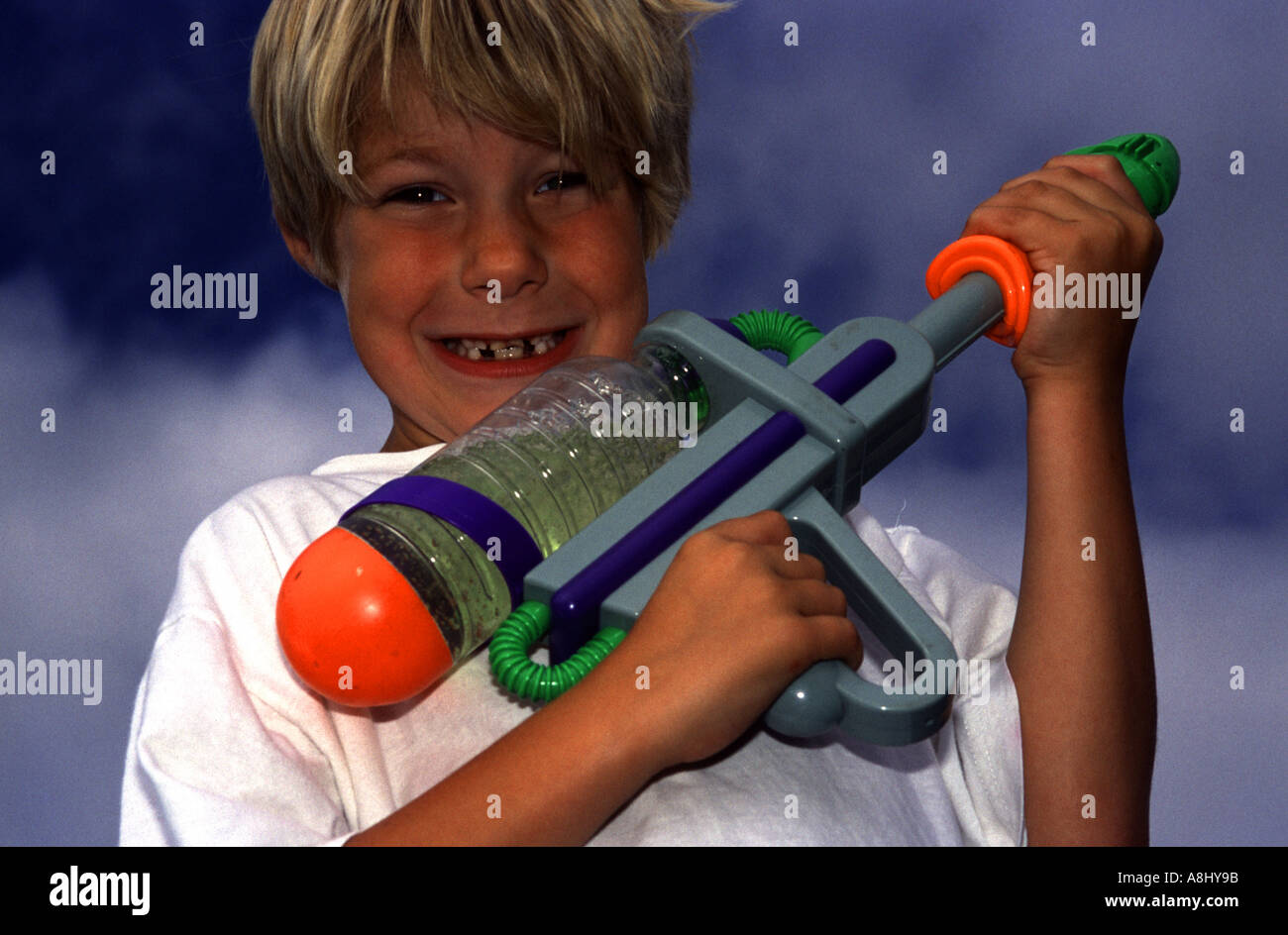 Boy smiling and armed with new toy water gun pistol Stock Photo Alamy