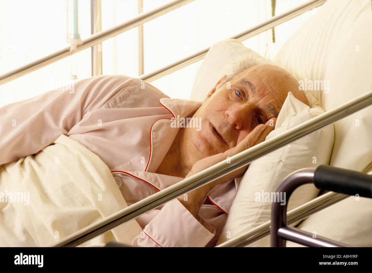 Elderly male patient despairing in hospital bed Stock Photo