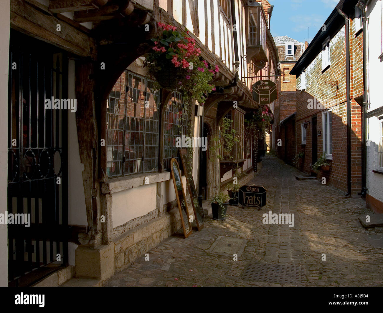 St Johns Alley featuring 15th century timber framed buildings on left, red brick houses and white painted frontage to right, Devizes, Wiltshire, UK Stock Photo