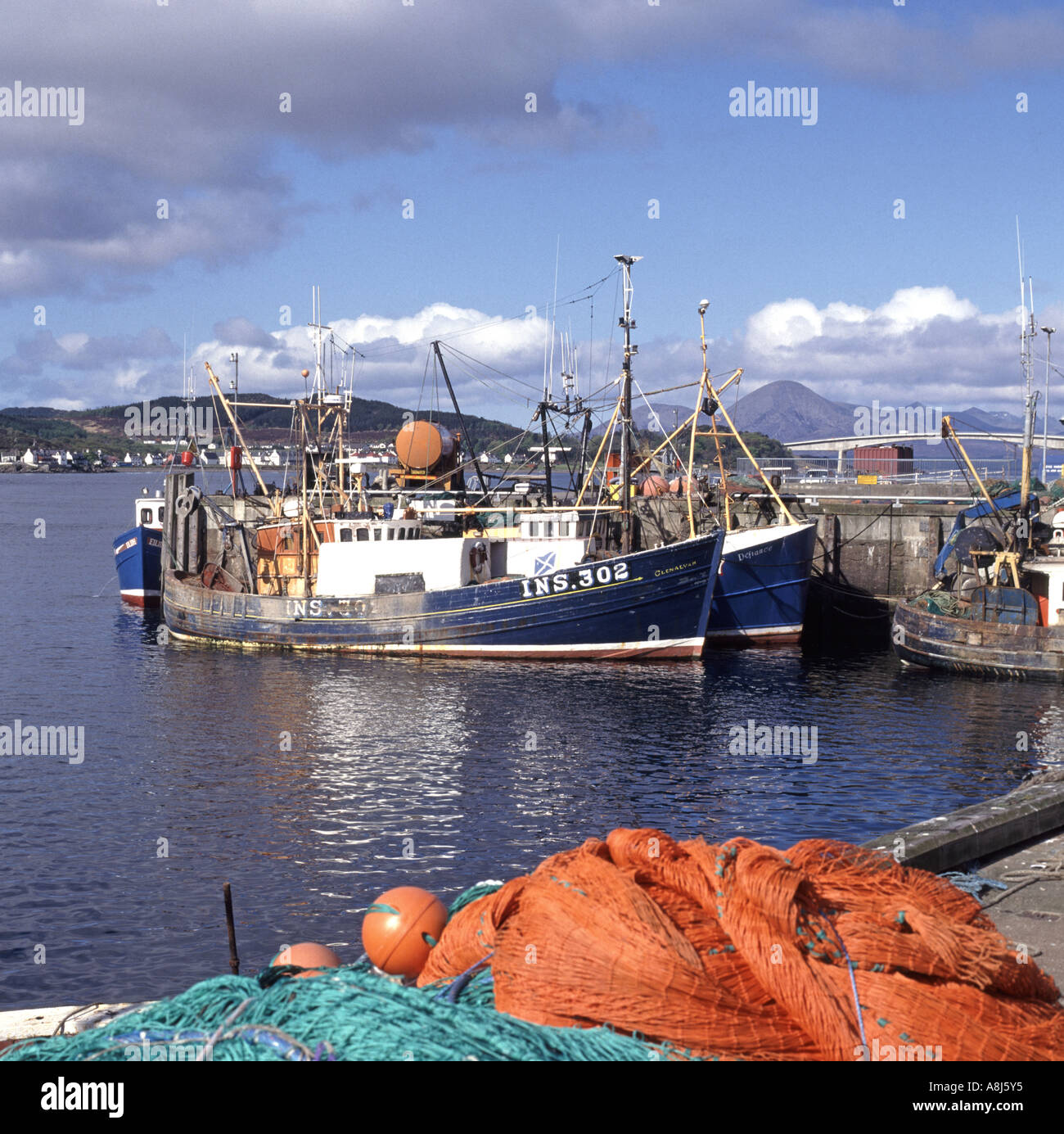 Loch Alsh Kyle Of Lochalsh harbour with fishing boat & nets Kyleakin village & one time toll bridge road on Isle of Skye beyond Highland Scotland UK Stock Photo