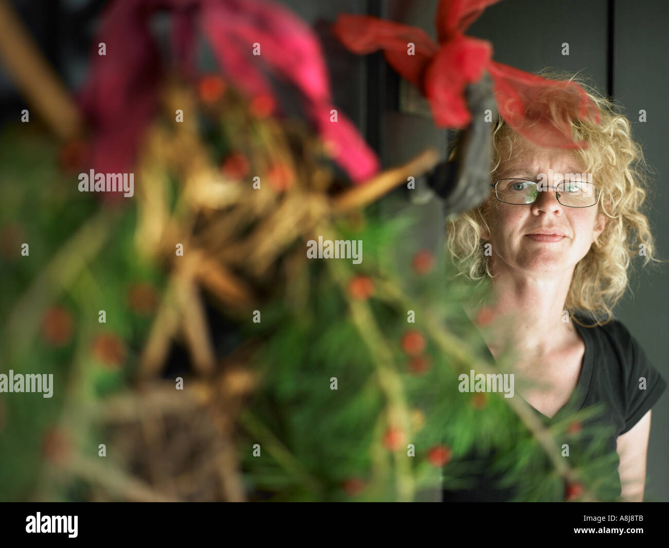 young woman at the front door with wreath decoration greeting christmas guests Stock Photo