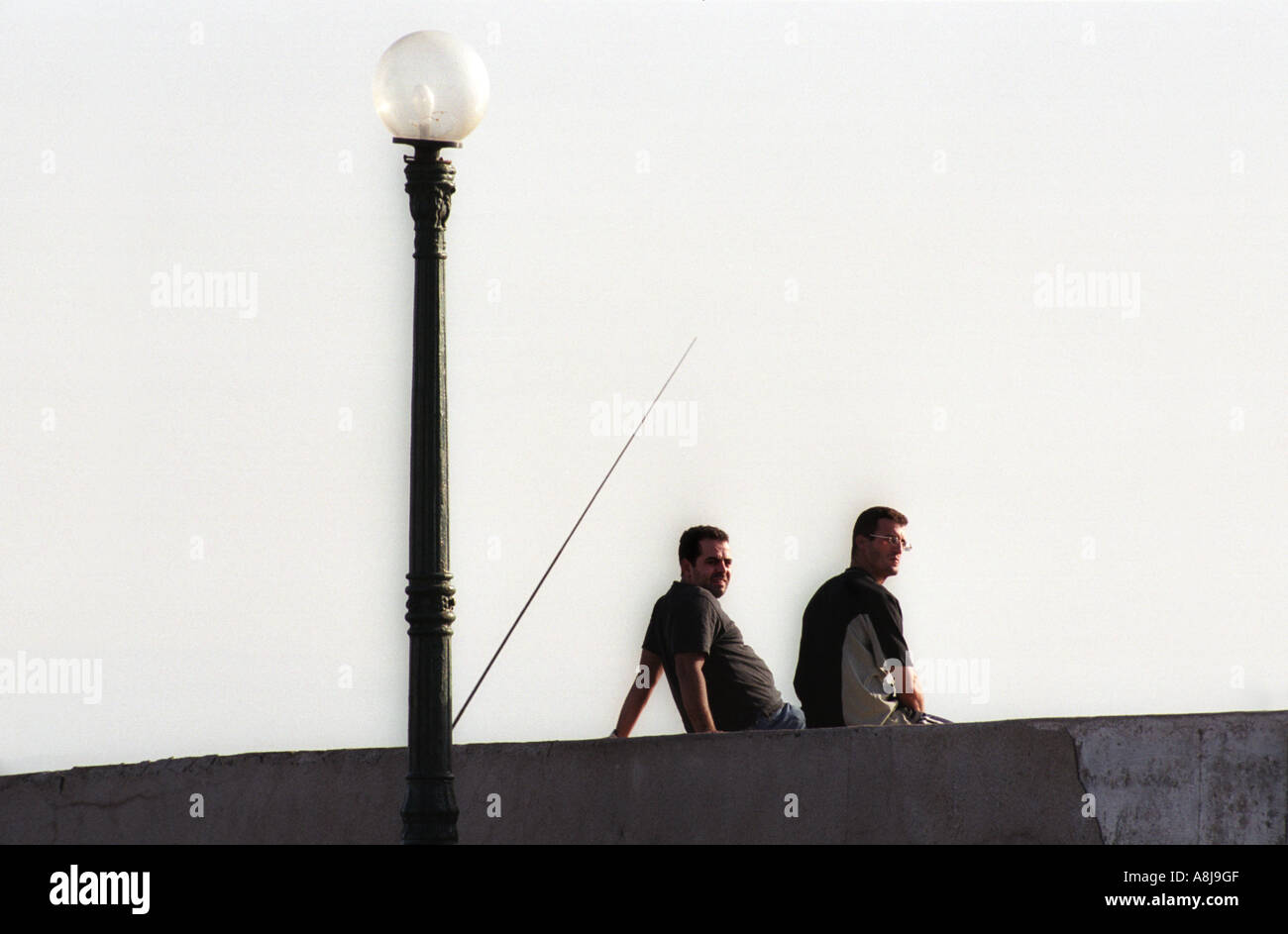 Two men sit on the quey at the fishing port of La Madrague outside Algiers in Algeria 2000 Stock Photo